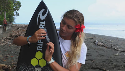 Video of woman with surfboard using burnd SPF41 sunscreen before going surfing on a beach in Costa Rica